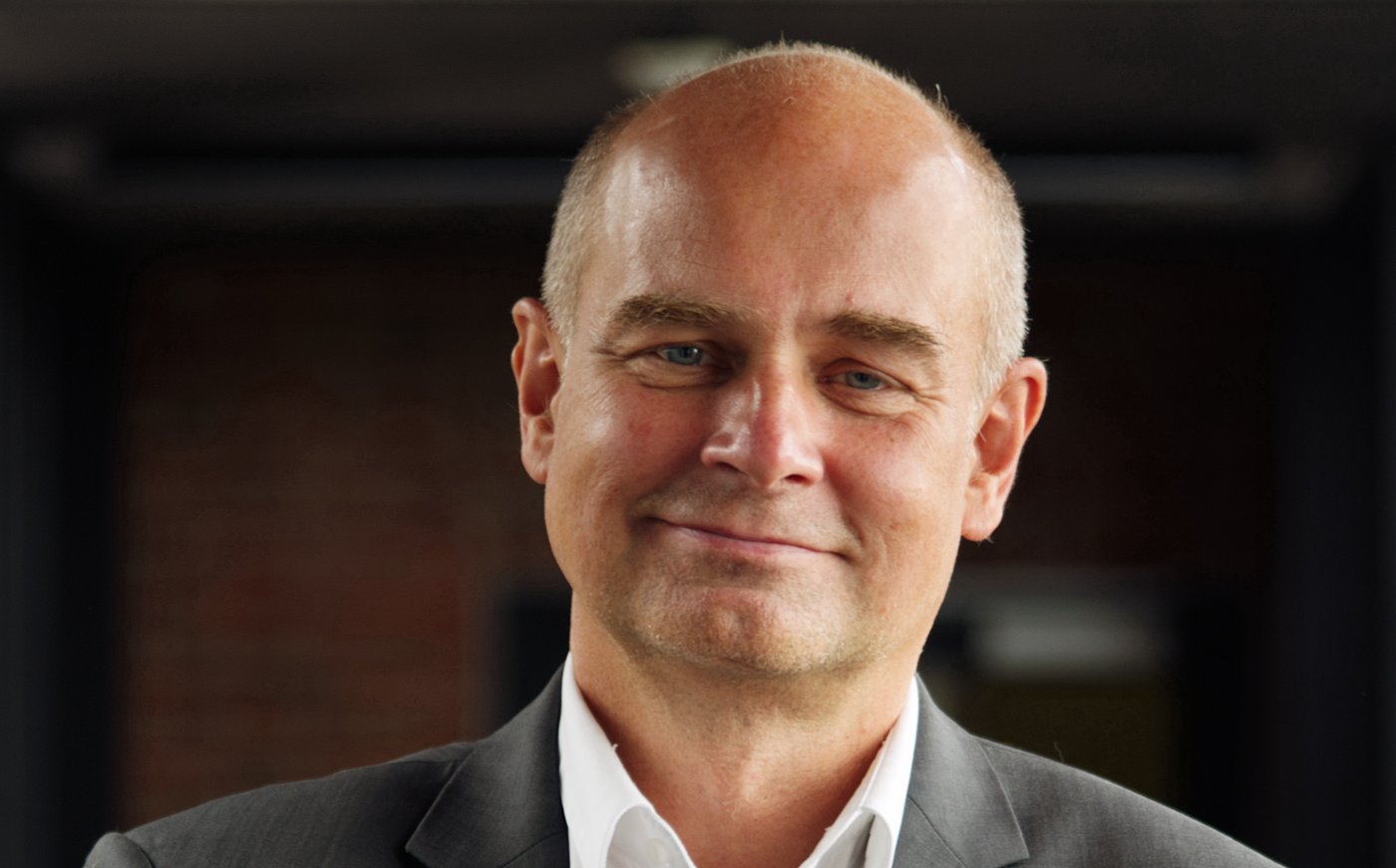 Prof. Dr Jürgen May: a researcher who is bald and wears a white shirt with a grey jacket.