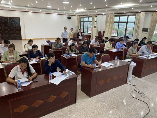 The picture shows participants completing a knowledge test during the training in Laos.
