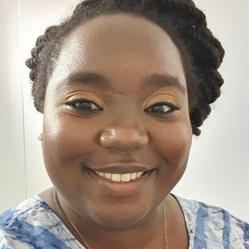 Dr Ndapewa Ithete: a smiling researcher wearing a blue and white batik blouse. In the background is a white wall.