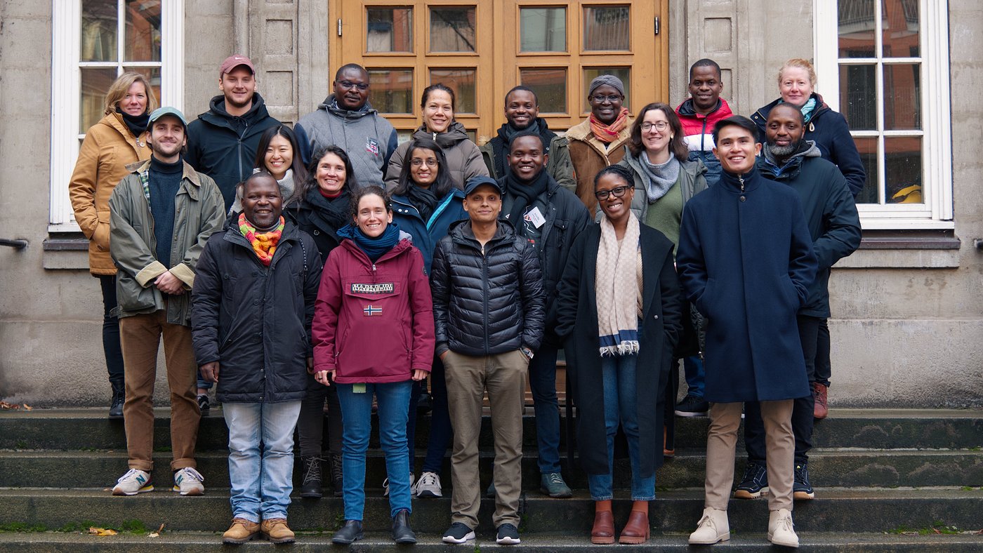 Gruppenbild der Teilnehmer:innen des EPICID Kurses. Zu sehen sind ist eine kulturell gemischte Gruppe freundlich lachender Teilnehmer:innen des EPICID Kurses. Die Teilnehmer:innen stehen auf einer Treppe vor einem antiken Gebäude und tragen dickere Jacken.