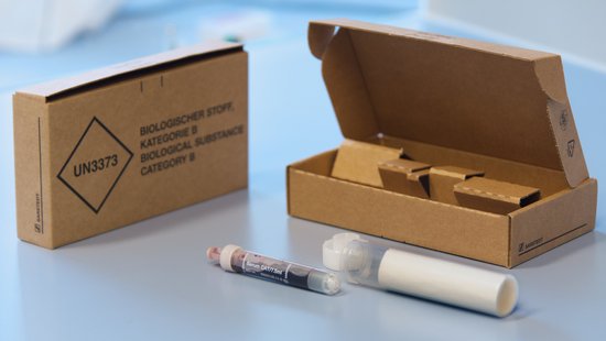 An example of a correct sample shipment is shown: A small brown cardboard box with the label UN3373. A milky plastic tube lies in front of it, lying open. Half of a blood tube is visible from the opening. The lid of the milky plastic tube lies in front of it.