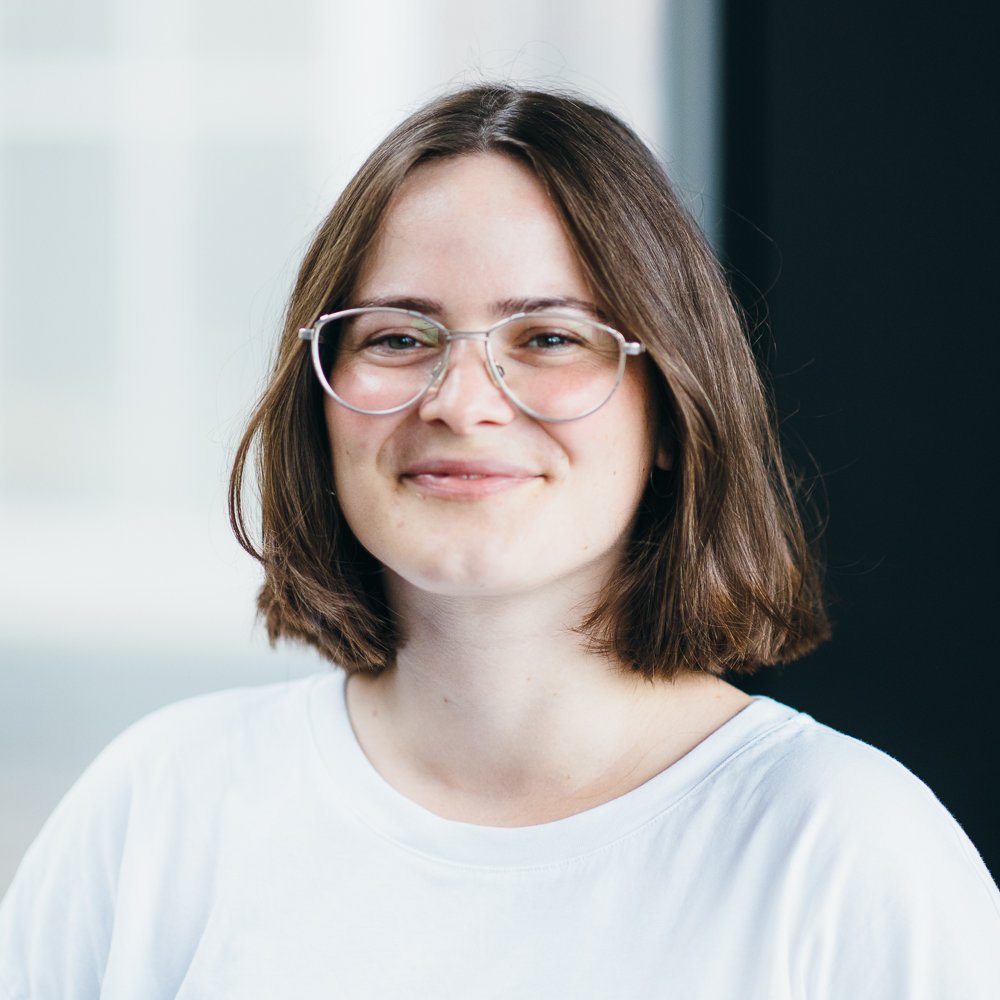 Portrait of a white female person with glasses and a long brown bob, wearing a white shirt.