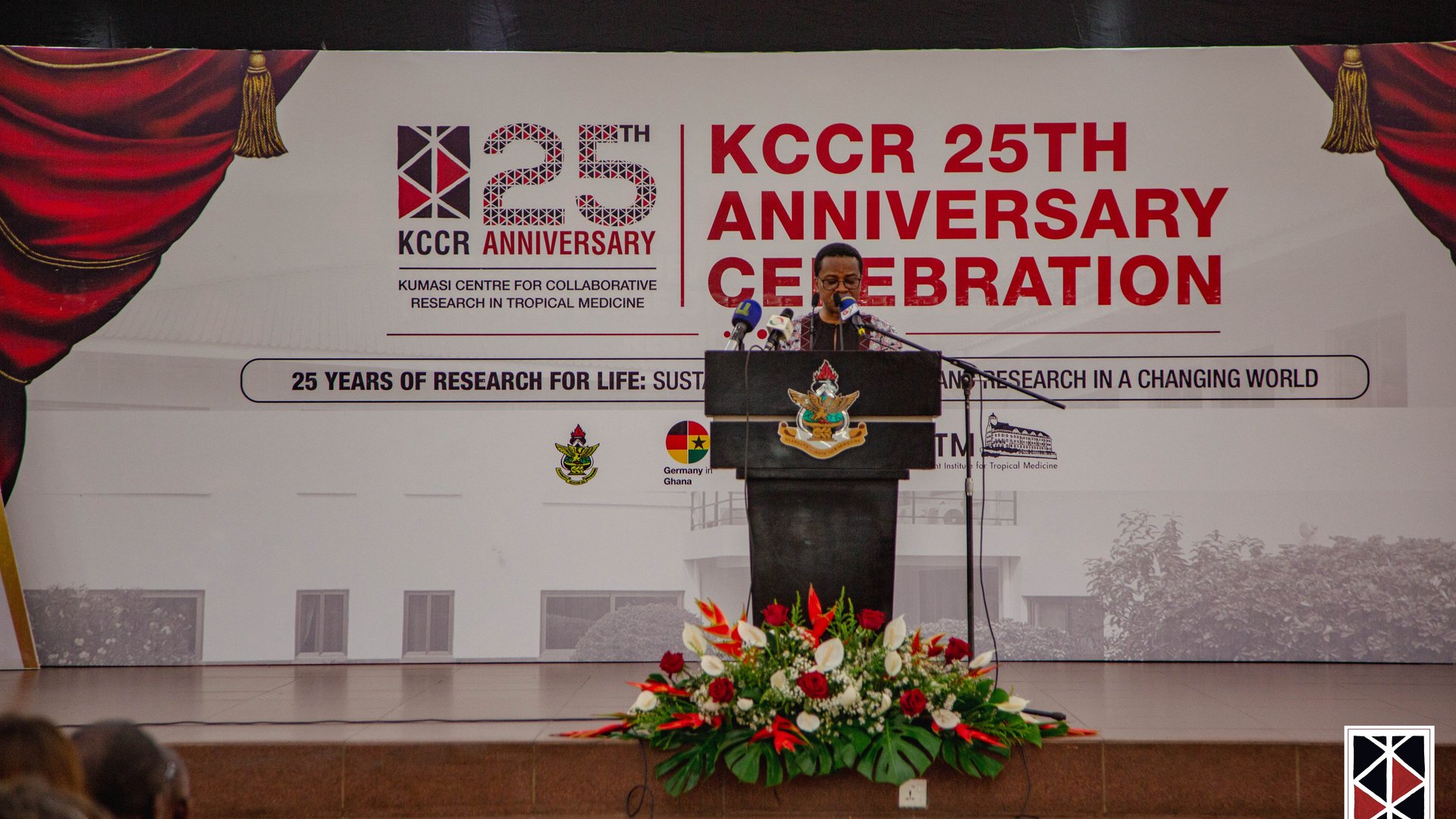 Der Wissenschaftliche Direktor des KCCR, Prof. Richard Phillips, steht am blumengeschmückten Pult und hält seine Rede.