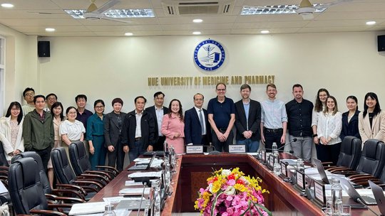 Das Bild zeigt mehrere Personen, die vor einem Logo der Hue University of Medicine and Pharmacy stehen.