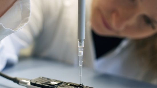 A woman working with test kits for pathogen research. She wears laboratory clothing