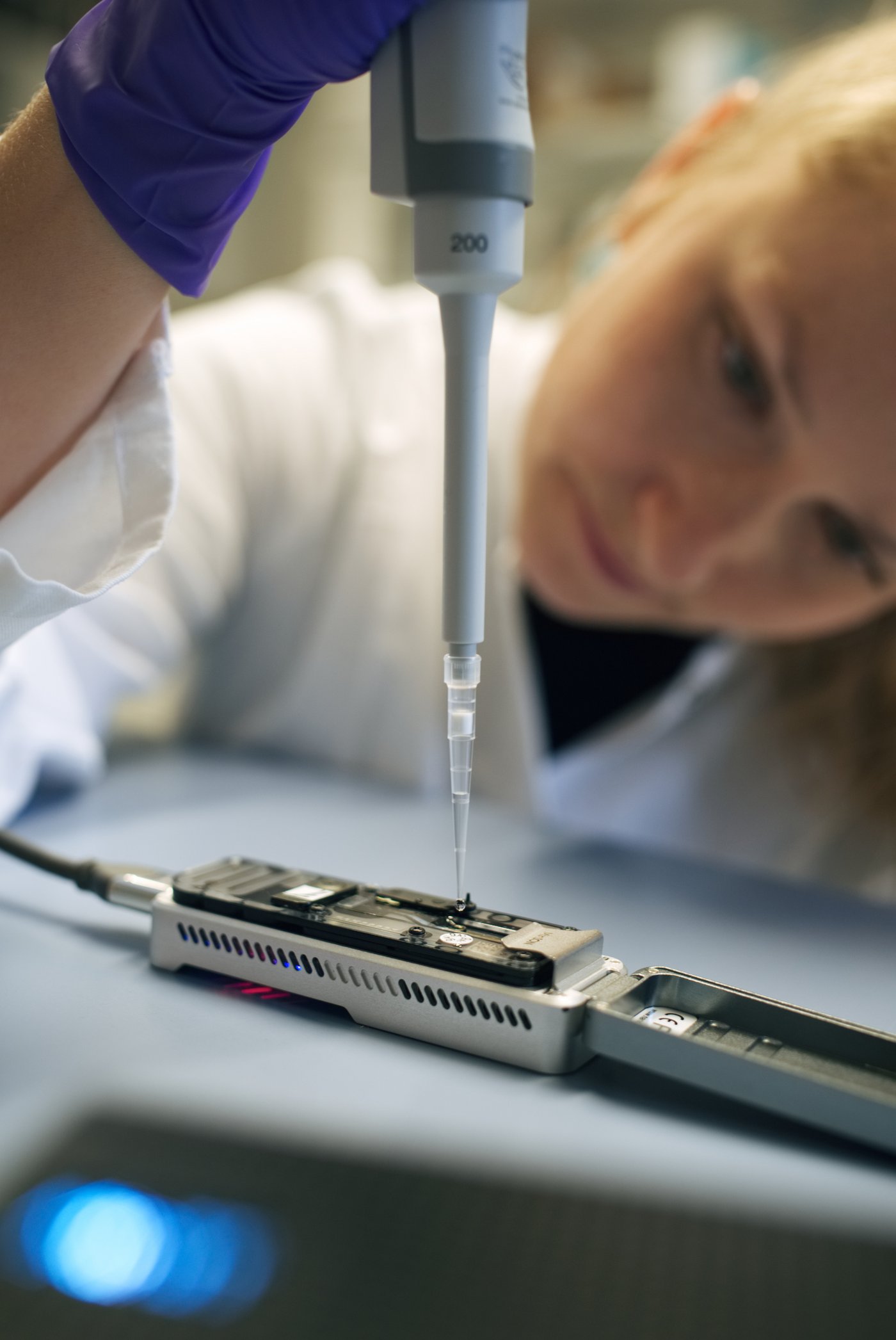 A woman working with pathogen research test kits. She wears lab clothes