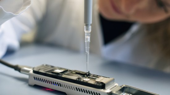 A woman working with test kits for pathogen research. She wears lab clothes