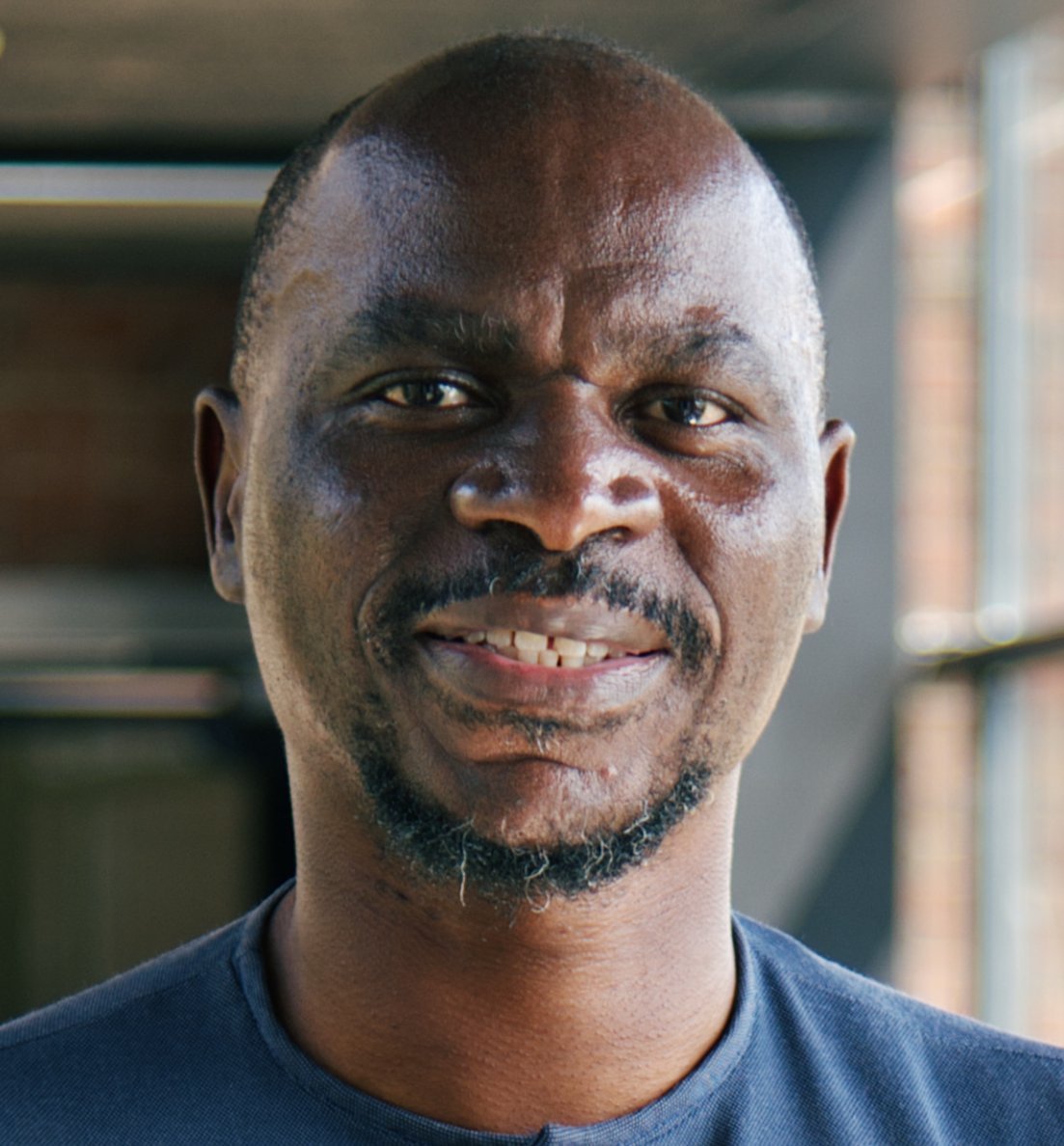 Porträt-Foto des gabonesischen Forschers Ghyslain Mombo-Ngoma: Er trägt Glatze, einen kurzen Vollbart und ein dunkelblaues afrikanisches Shirt und lächelt in die Kamera.