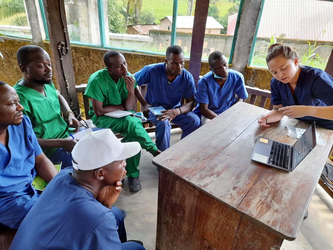 A class room scene in Guinea. A trainer is explaining something shown on a laptop, while six Guinean laboratory staff are listening.