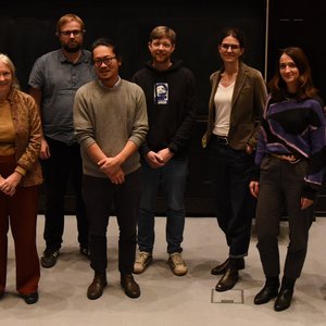 The photo shows ten researchers standing in front of a screen in the lecture hall.