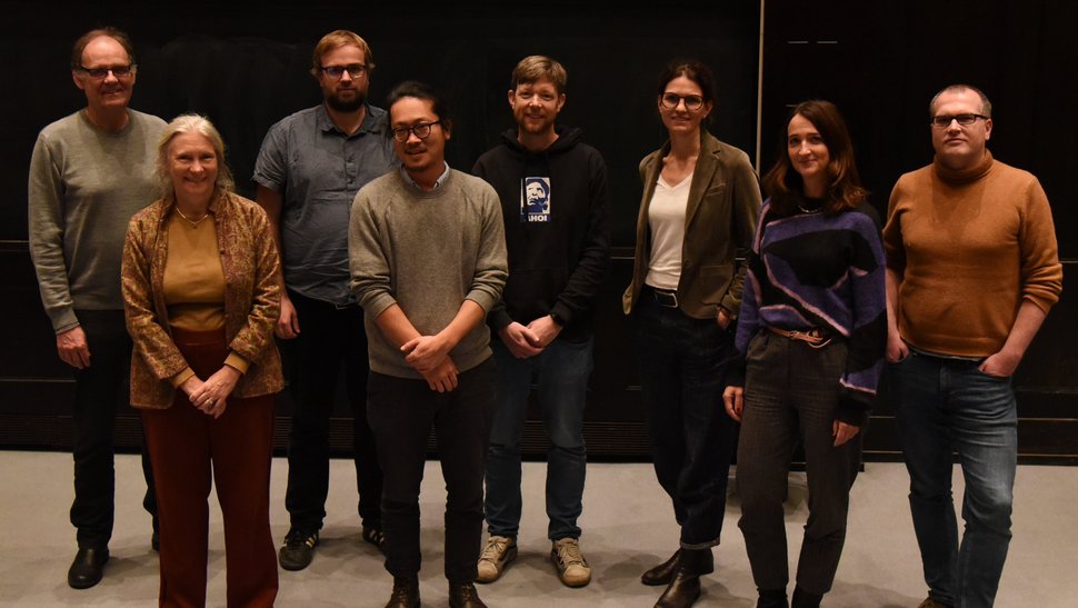 The photo shows ten researchers standing in front of a screen in the lecture hall.