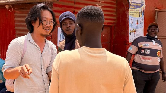 Das Foto zeigt einen Forscher mittleren Alters im Gespräch mit mehreren Männern in Ituri/ DRC