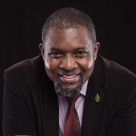 PhD John Amuasi: a researcher wearing a suit, dark short hair and a short beard.