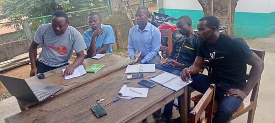 Five laboratory staff in front of a laptop listening and taking notes during theoretical training.