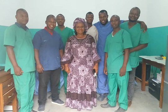 Laboratory staff of the LFHV-GKD in the new sequencing room together with the general director of the DPS Guéckédou at the inauguration day. Guéckédou, Guinea, December 2025. Several laboratory staff are pictured in their professional lab scrubs. One woman in the middle wears a traditional dress.