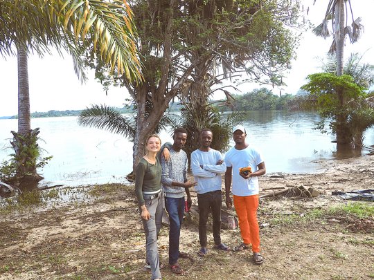 Eine gemischte Gruppe von Menschen steht an einem ruhigen Gewässer und unterhält sich freundschaftlich.