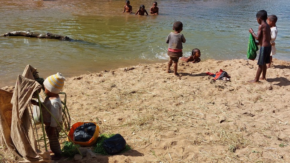 Das Foto zeigt Kinder in Madagaskar an einem Fluss spielen und baden.