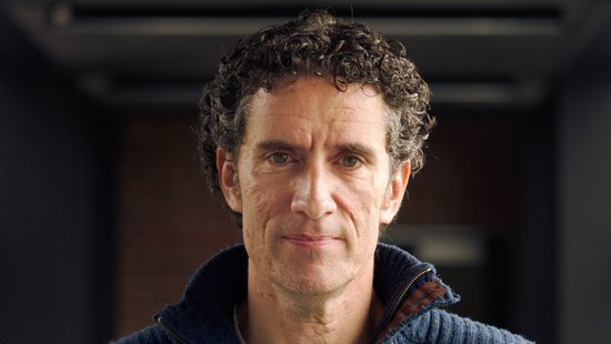 Prof. César Muñoz-Fontela: Ein Forscher mit kurzen Locken, der einen blauen Wollpullover trägt.
