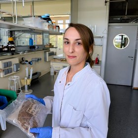Photo of Louisa Jahn Photo showing a woman with brown hair in a laboratory, wearing a lab coat.