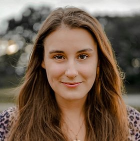 Chiara di Sciullo Chiara di Sciullo: eine technische Assistentin, die in Richtung Bildbetrachter schaut. Sie hat langes, offenes dunkelblondes Haar und trägt ein gemustertes Oberteil.