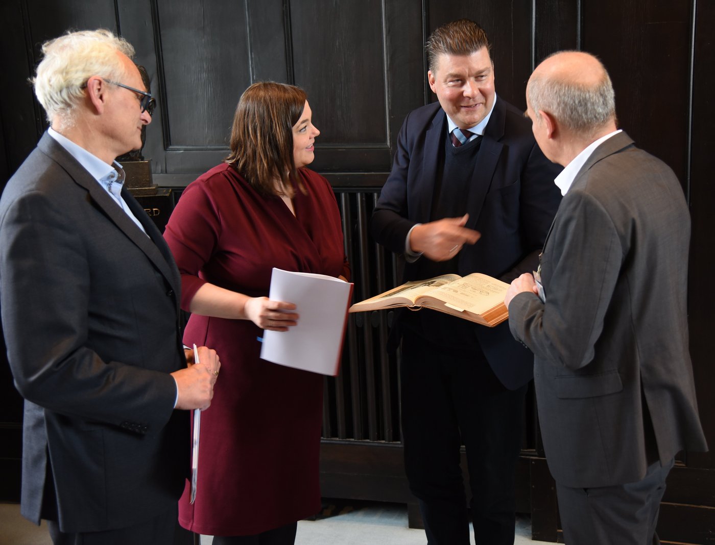 Das Bild zeigt v.l.n.r. Martin Görge, Katharina Fegebank, Andreas Dressel und Jürgen May. Sie beugen sich über ein historisches Buch über das BNITM von 1914.