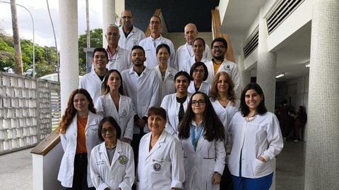 An international group of academic and public health stakeholders from the Americas standing on outdoor building steps, dressed in white professional attire, smiling and laughing together.