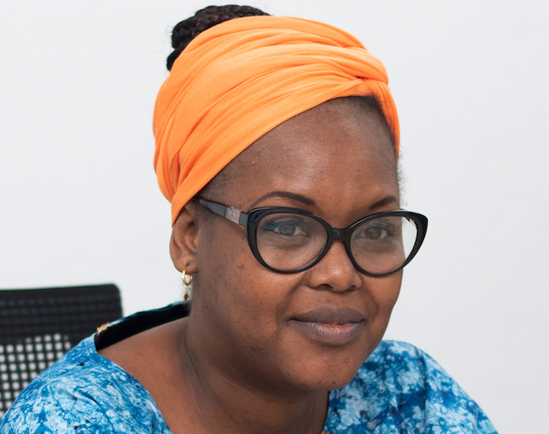 Porträtfoto der erfahrenen Forscherin Dr. Oumou Maïga-Ascofaré. Sie trägt ein oranges Kopftuch, eine dunkel umrandete Brille, ein dunkelblaues Oberteil und eine gemusterte hellblaue Jacke.