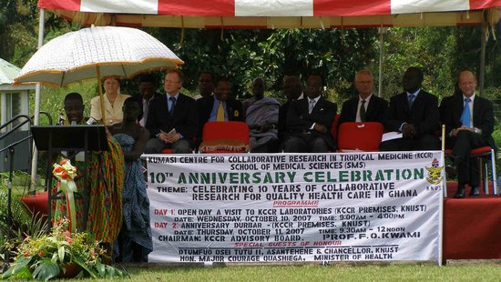 Eine Gruppe sitzt auf einer Bühne, im Vordergrund ein Banner mit 10th Anniversary