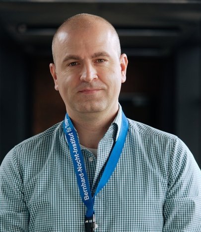 Dr. Dániel Cadar: ein Forscher, der ein blau-weiß kariertes Hemd trägt und eine Glatze hat.