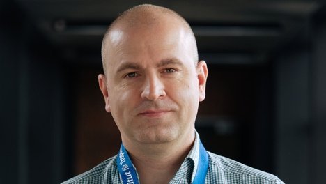 Dr. Dániel Cadar: ein Forscher, der ein blau-weiß kariertes Hemd trägt und eine Glatze hat.