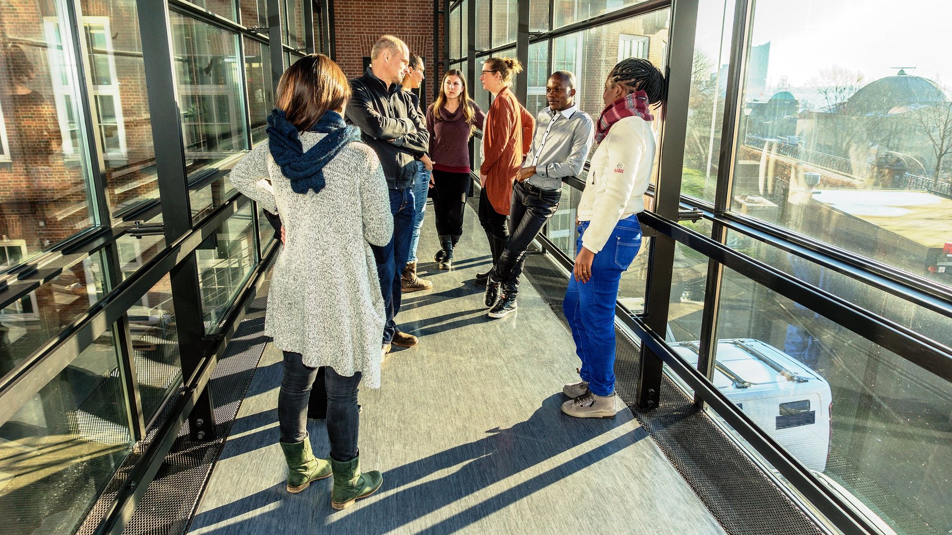 Gruppe von Alumnis im Brückenübergang des Insituts bei Sonnenlicht.