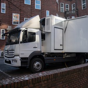 A white lorry with the word MOBILISE is parked in front of a red-brick building.