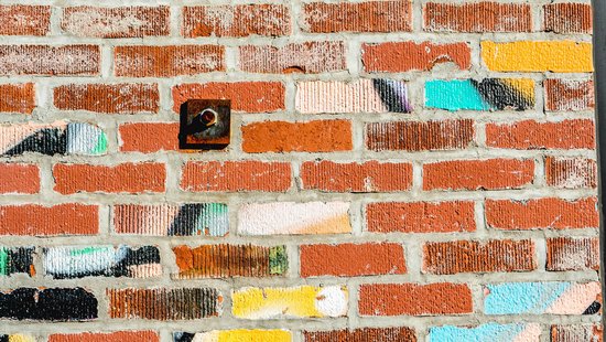 Bild von einer Backsteinmauer mit einzelnen bunten Backsteinen