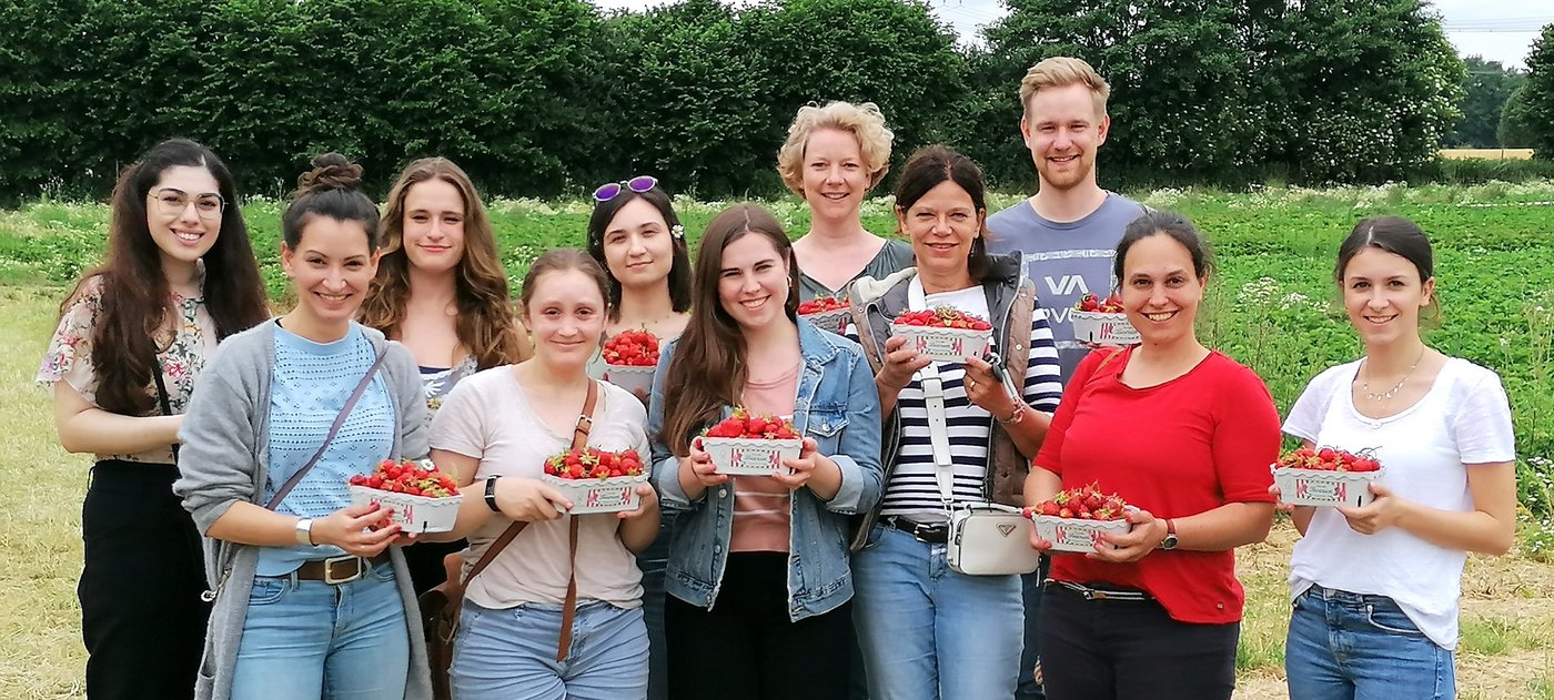 Auf dem Bild sind gut gelaunte Mitarbeiter der AG Lotter mit Erdbeerschalen in der Hand zu sehen