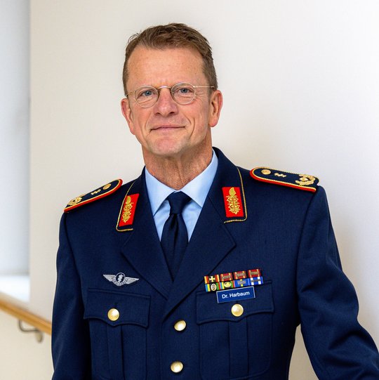 Thomas Harbaum Das Foto zeigt einen Herren, Generalarzt Dr. Harbaum, in Uniform. Er hat braune kurze Haare und trägt eine Brille.