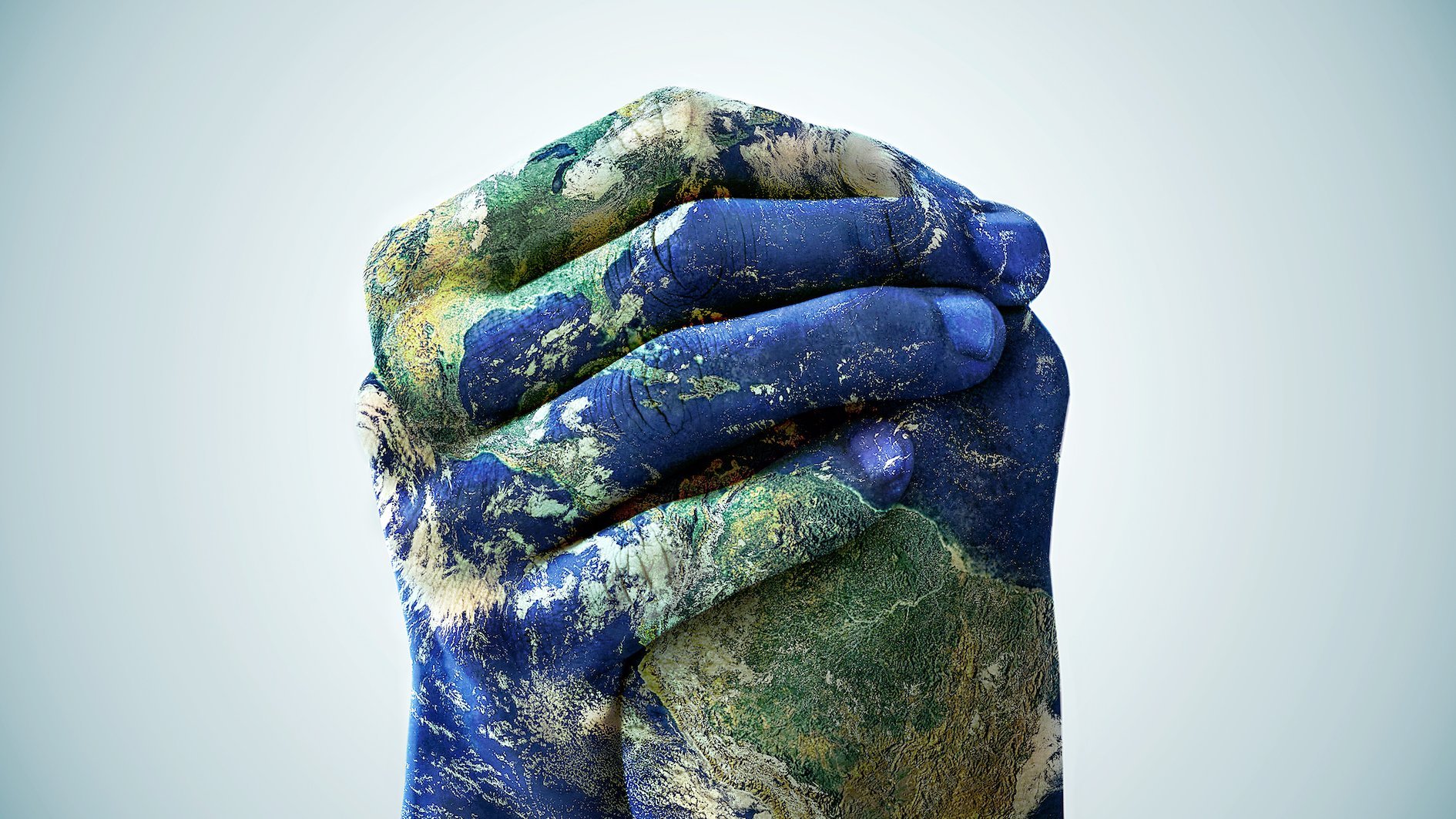 Das Foto zeigt zwei ineinander verschränkte blau-grün gefärbte Hände. Sie scheinen die Welt mit ihren Ozeanen und Kontinenten in der Hand zu haben.