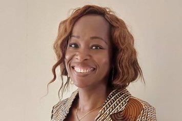 Dr. Rella Zoleko Manego Die Forschungsgruppenleiterin Dr. Rella Zoleko Manego aus Gabun. Sie trägt einen bräunlich-weiß-bunten Blazer und lächelt freundlich in die Kamera.