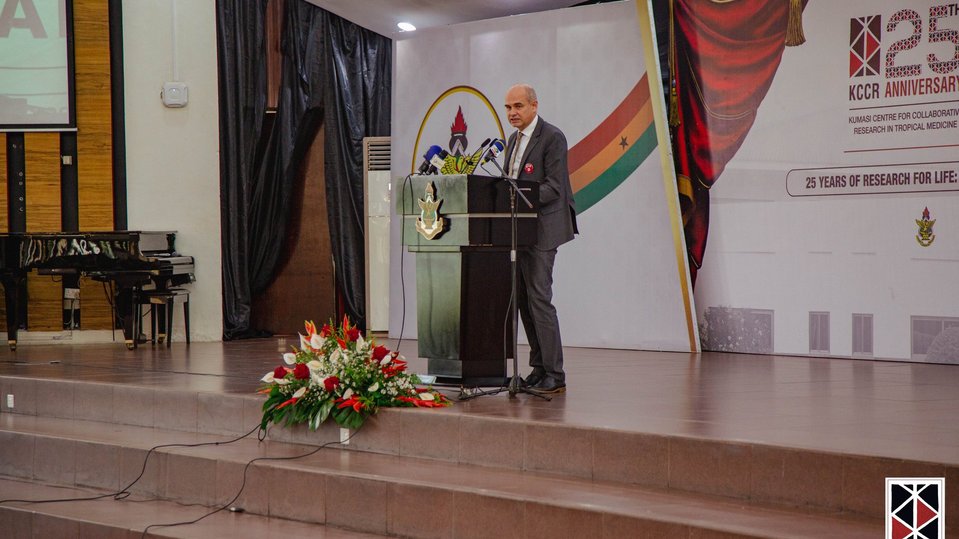 The Chairman of the Board of the BNITM, Prof. Jürgen May, stands at the lectern adorned with flowers and gives his speech.