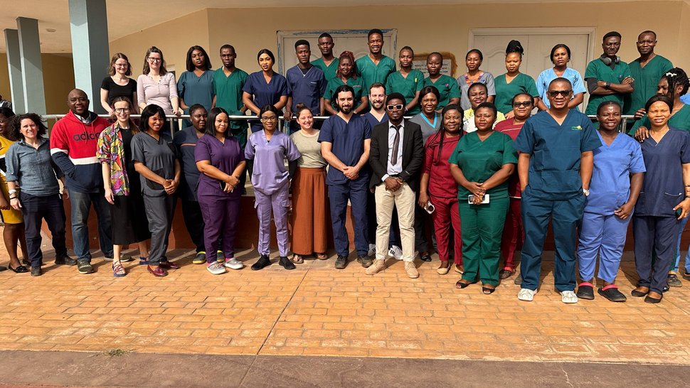 Group picture of the international cross-institutional team standing outside in front of a building and smiling.