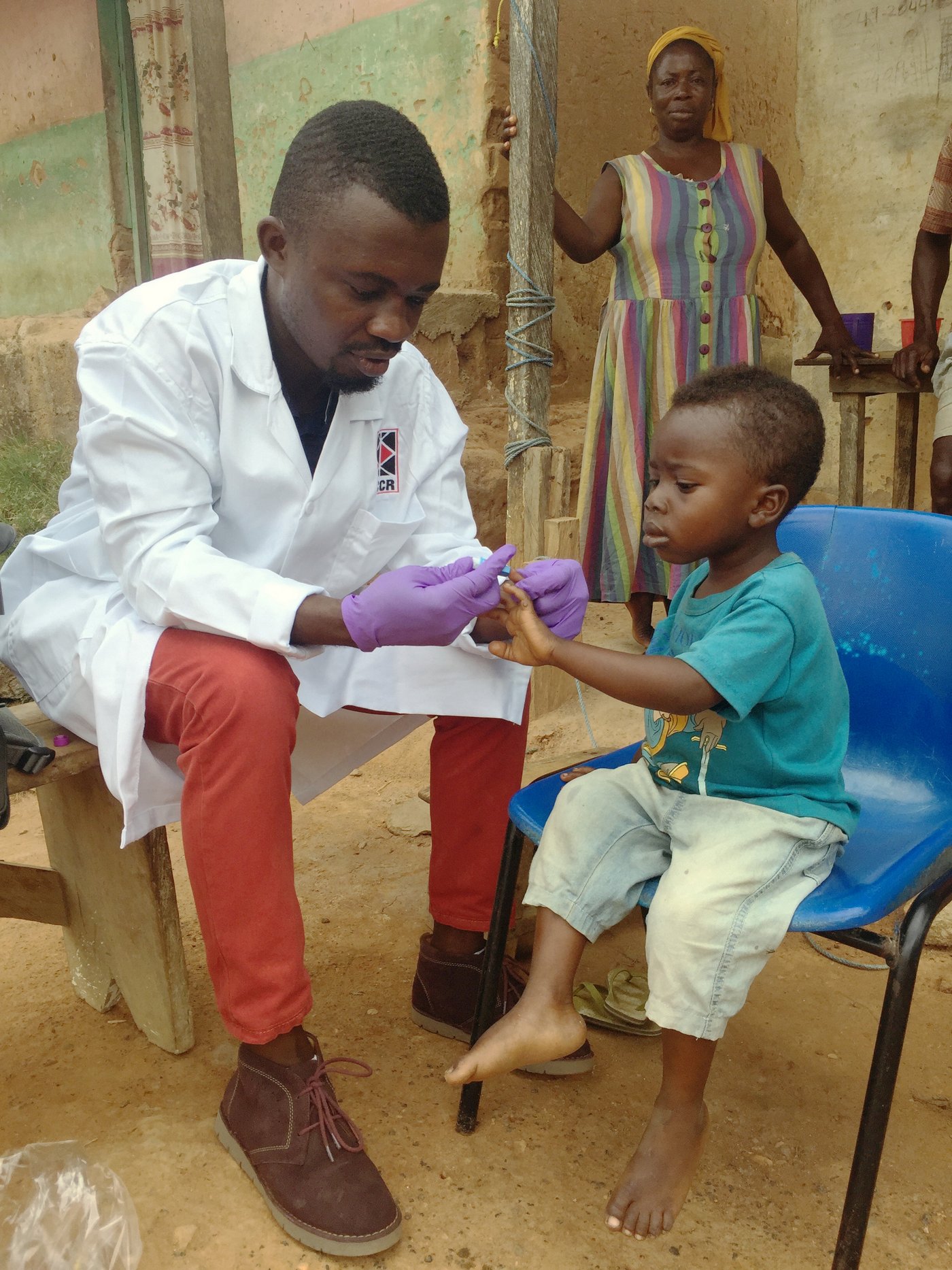 Nachuntersuchung eines an Malaria erkrankten Kindes. Das Bild zeigt einen afrikanischen Arzt bei der Blutentnahme bei einem Kleinkind zur Malaria-Diagnostik
