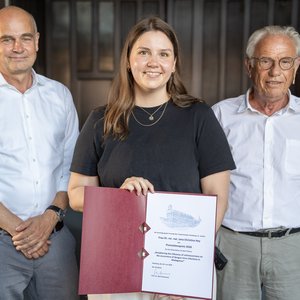Foto: v.l.n.r. Jürgen May, Jana Hey, Rolf Horstmann im historischen Hörsaal, im Hintergrund einige Zuhörer:innen.
