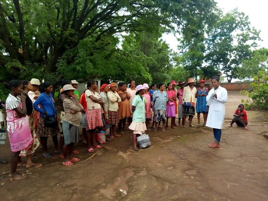 Eine große Gruppe schwangerer Frauen steht vor einer Pflegerin, die anhand eines Zettels der Gruppe etwas erklärt. Die Gruppe steht draußen im Grünen.