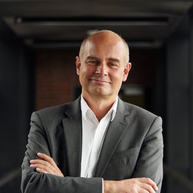 Prof. Dr. Jürgen May:ein Forscher, der eine Glatze hat und ein weißes Hemd mit grauem Sakko trägt.
