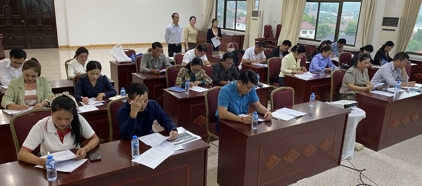 Das Bild zeigt Teilnehmende, die einen Wissenstest während der Schulung in Laos absolvieren.