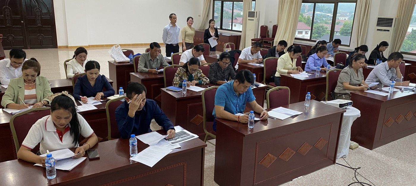 The picture shows participants completing a knowledge test during the training in Laos.