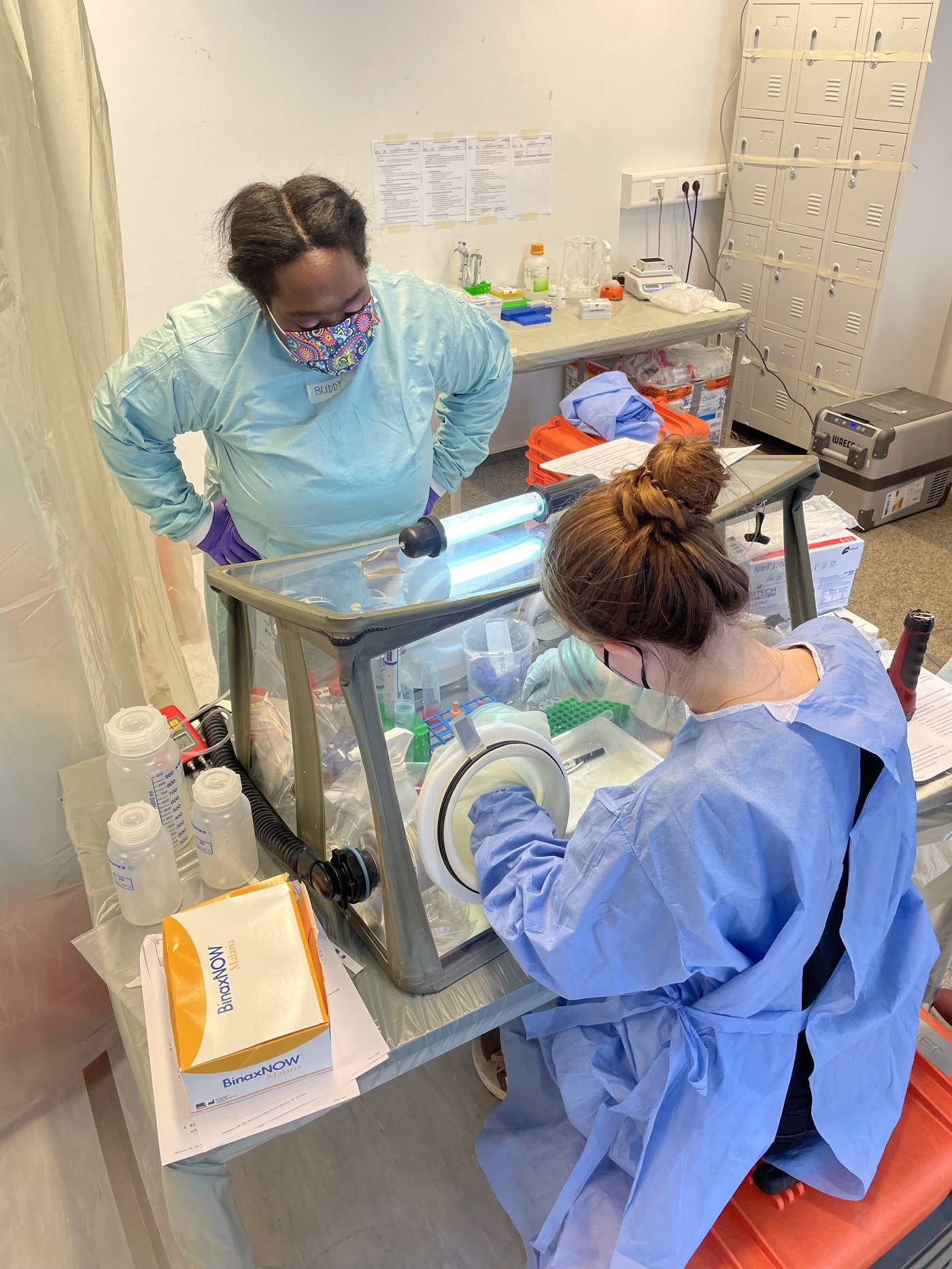 One scientist works with the so-called glove box, another watches.