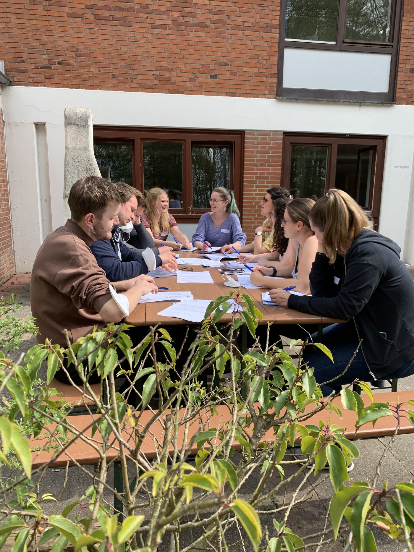 Participants of the LCI Summer School Workshop are seen working at a table in the garden.