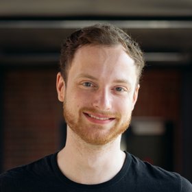 Lennart Heepmann: A doctoral student in a black shirt smiles at the camera. He has short red-brown hair and a red three-day beard.