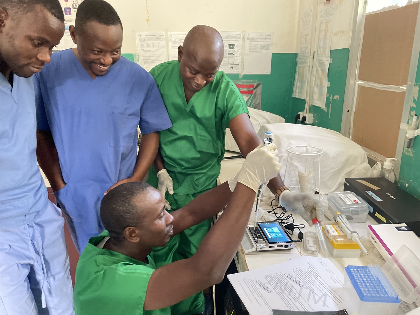 A laboratory in Guinea: One lab staff member is loading a flow cell while three colleagues are observing.