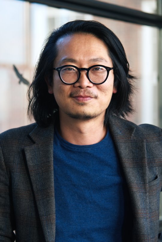 Dr. Sung-Joon Park: ein Forscher der schulterlanges Haar, eine runde schwarze Brille, ein dunkles Sakko über einem dunkelblauen Oberteil trägt.